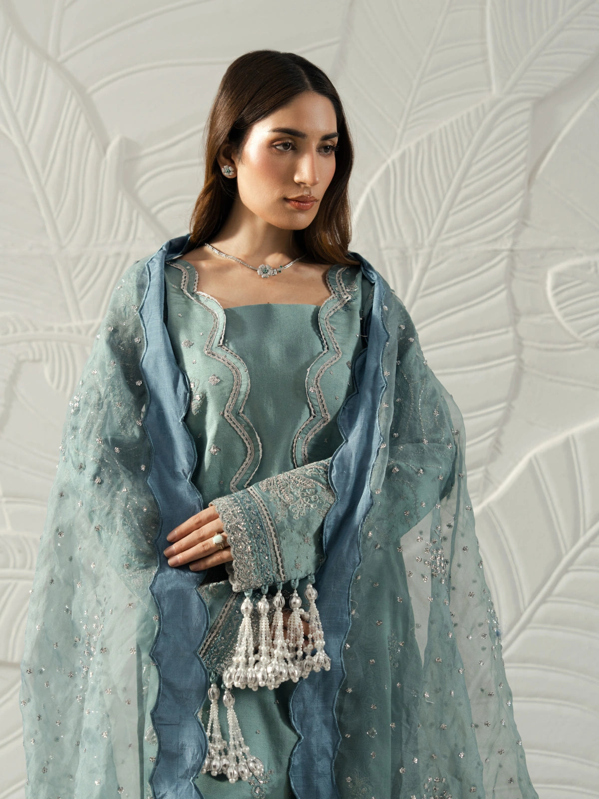 Model wearing a sage green embroidered kameez with a matching dupatta and blue border.
