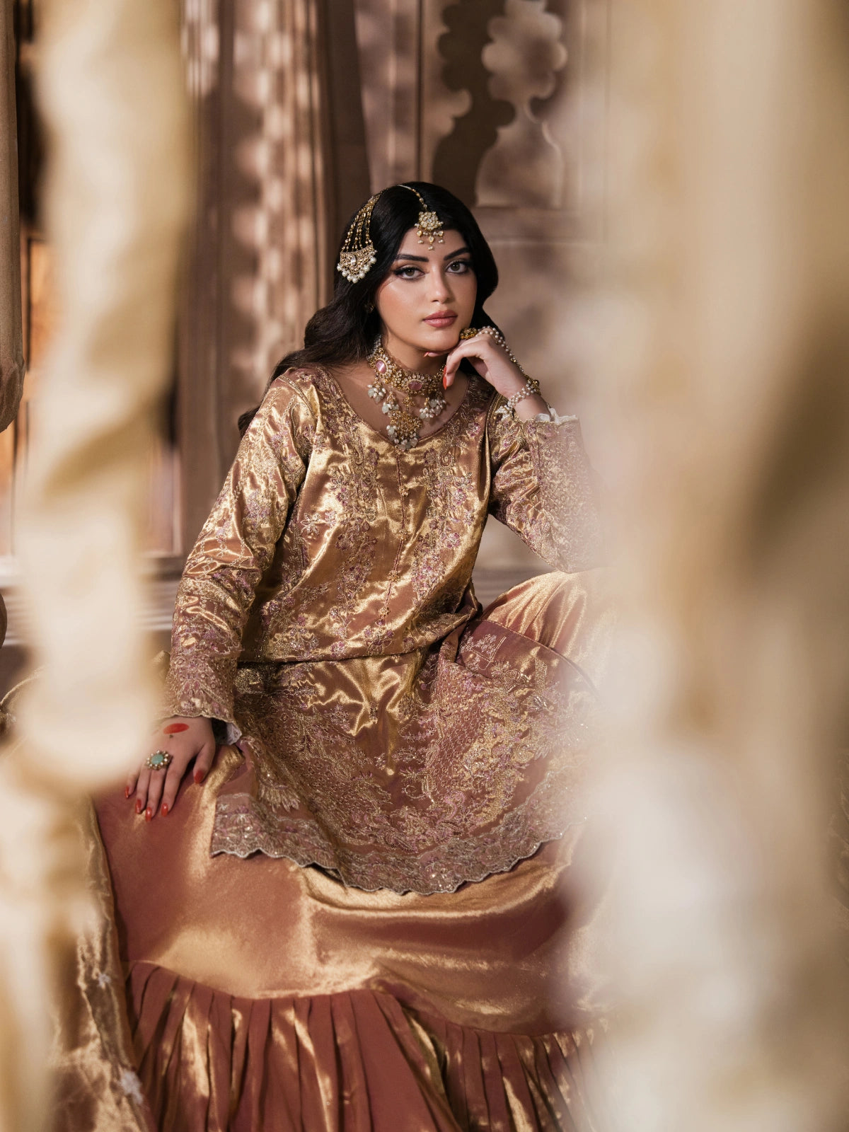 Full-length view of a gold bridal gharara with a decorative hem
