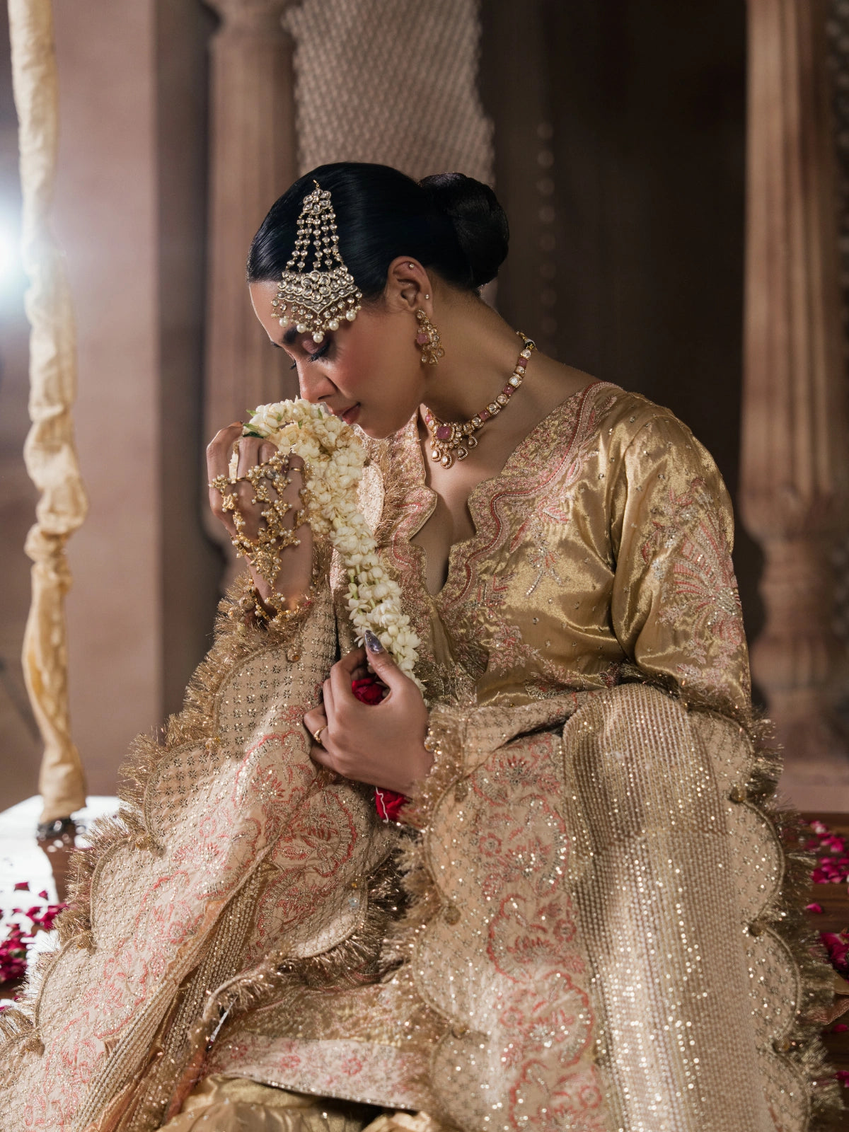 Bridal fashion featuring a gold outfit photographed in a traditional palace setting