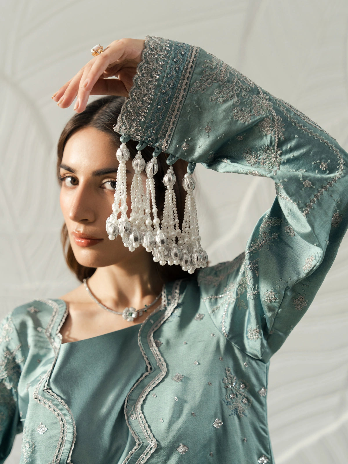 Women's sage green formal outfit with embroidered sleeves, matching trousers, and a sheer dupatta.