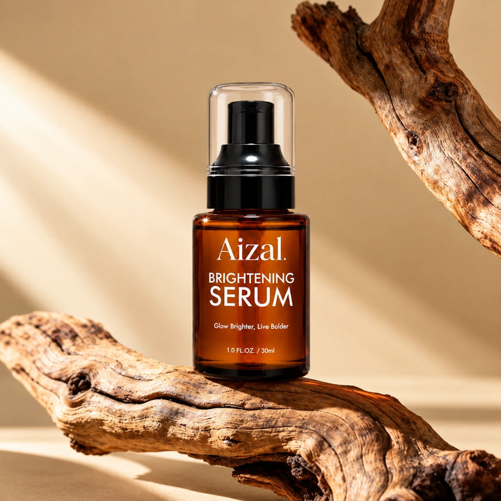 Brightening Serum in an amber glass bottle with a black pump and clear cap, displayed on a piece of driftwood against a warm beige background.
