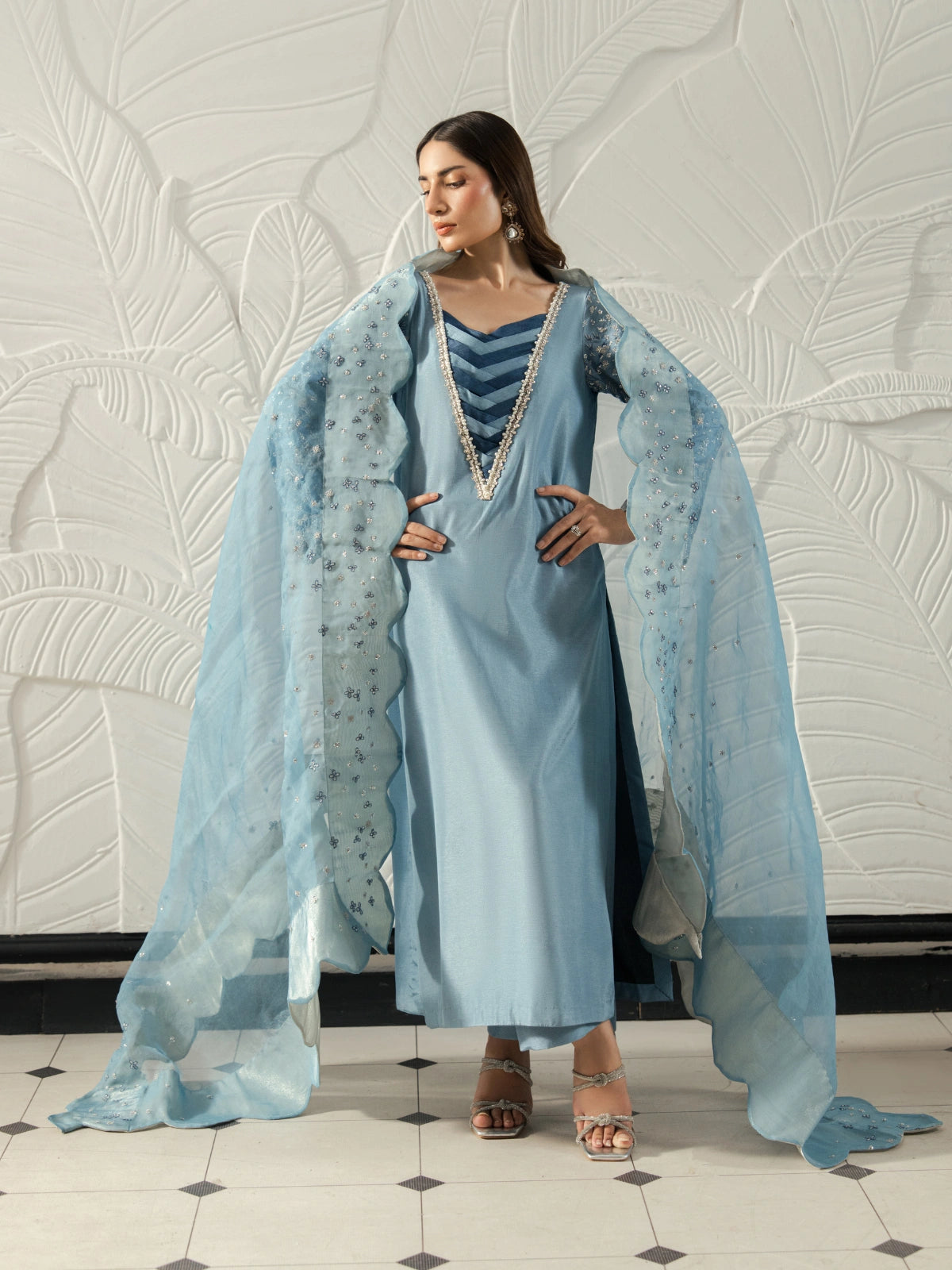 Pakistani women's sky blue outfit featuring a V-neck design with silver detailing and a flowing dupatta.